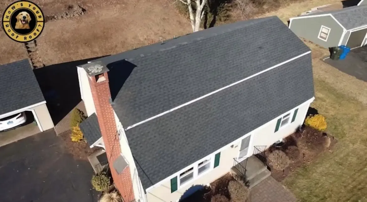 Beige home with a new grey shingle roof, brick chimney and green shutters
